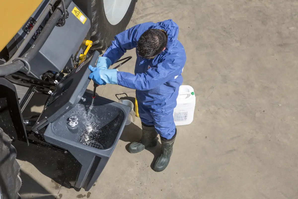 Operator preparing water beside an agricultural sprayer